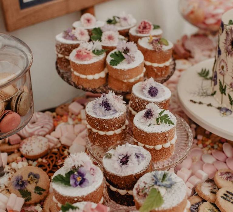 Wedding cupcakes on cake table at wedding with Prosecco wall