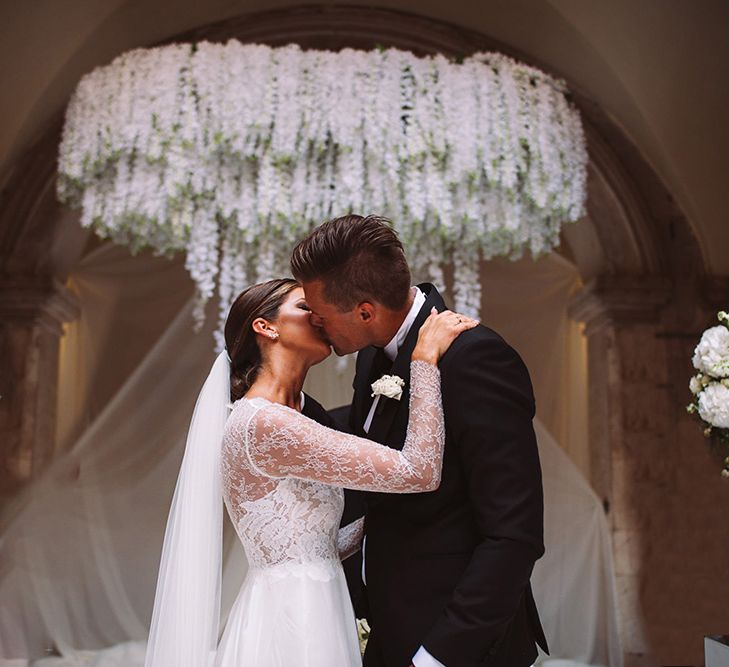 Bride and Groom Just Married Kissing at The Altar with Floral Chandelier Backdrop