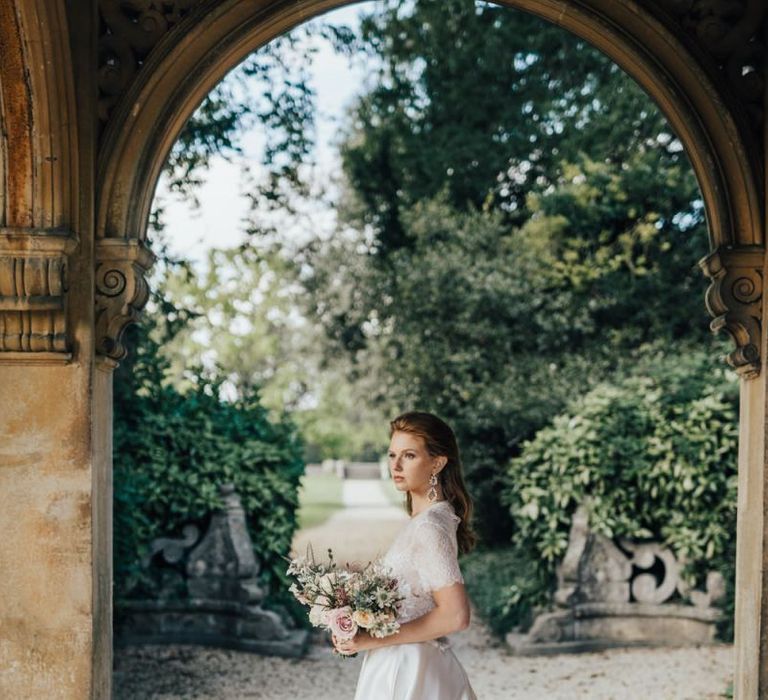 Bride Standing in a Courtyard Holding a Bouquet