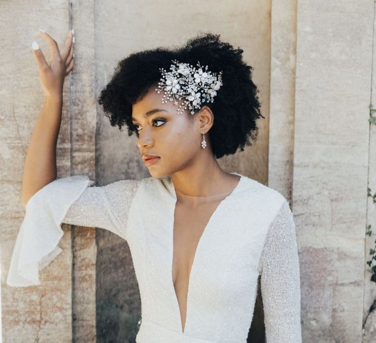 Black Bride with Afro Hair Wearing an Ornate Pearl Hair Accessory and Shimmering Emma Beaumont Wedding Dress