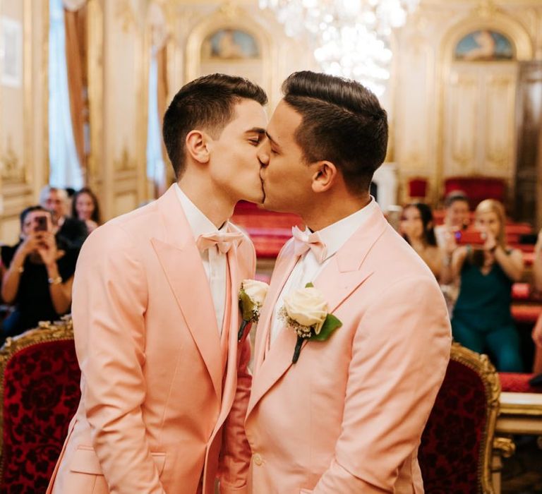 First kiss between both grooms wearing pink wedding suits