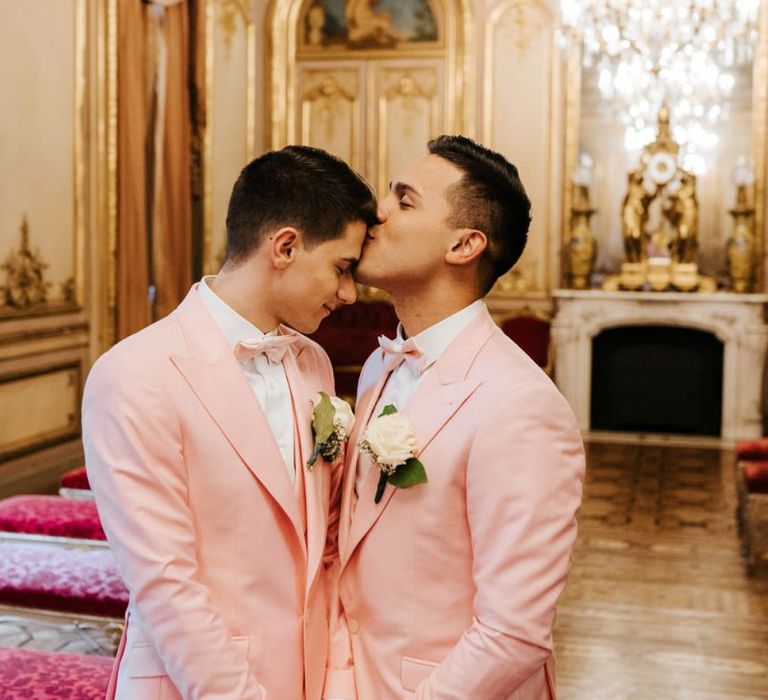 Grooms embrace at intimate Paris same-sex celebration wearing pink wedding suits