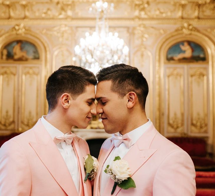 Grooms embrace at intimate Paris same-sex ceremony wearing pink wedding suits