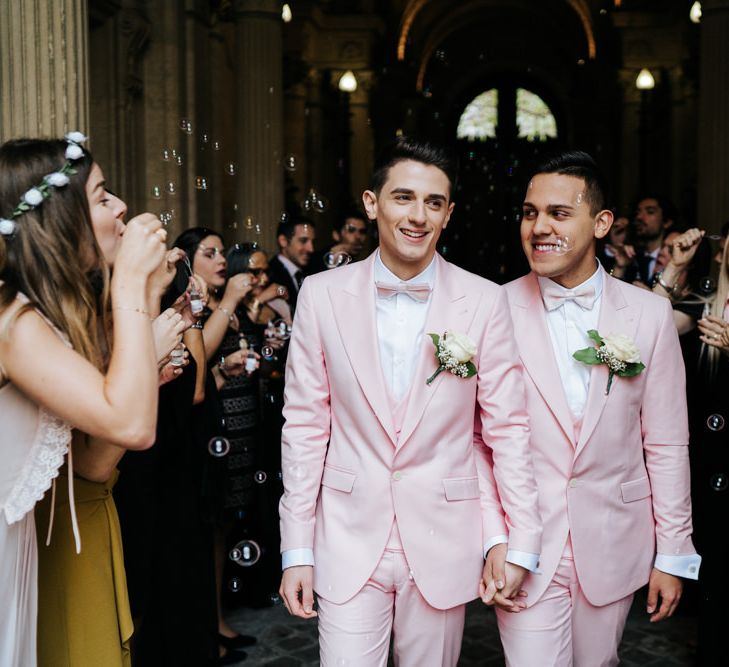 Grooms wearing pink wedding suits walk through a bubble tunnel at Paris same sex wedding