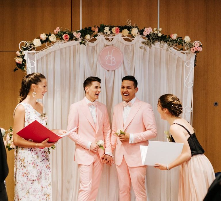 Grooms wearing pink wedding suits with personalised aisle arch decor at second Paris intimate ceremony