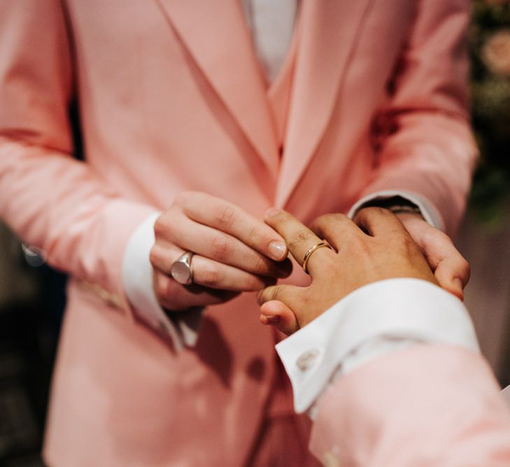 Grooms placing the wedding bands on each others finger