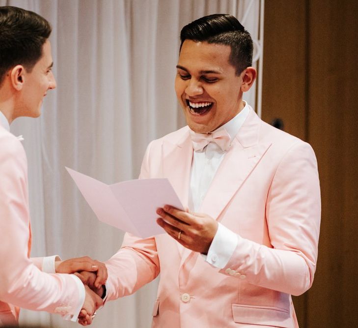 Grooms holding hands as they read their personalised wedding vows