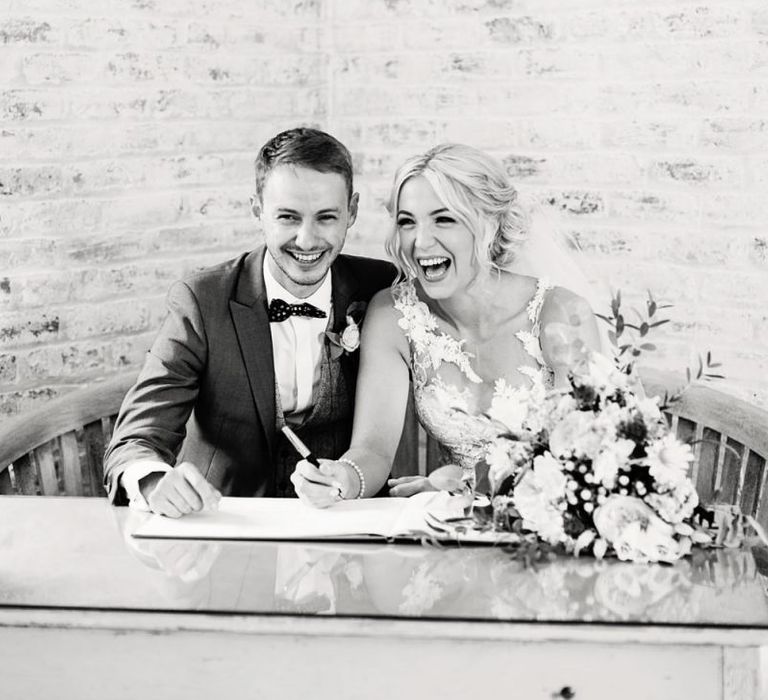 Bride in Lace Pronovias Wedding Dress and Groom in Navy Suit Signing the Register