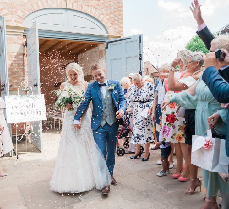 Confetti Moment with Bride in Pronovias Wedding Dress and Groom in Navy Suit