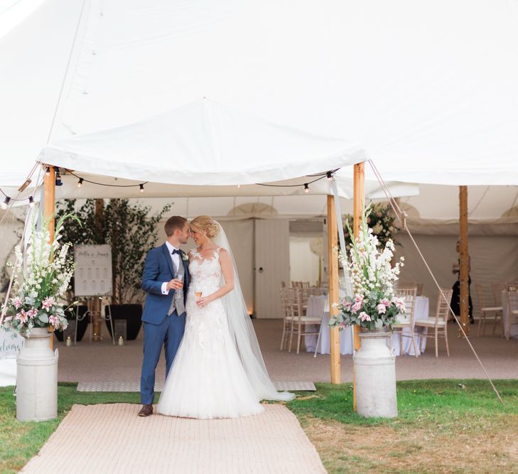 Bride in Pronovias Wedding Dress and Groom i Navy Suit Standing in Front of Their Sperry Tent Marquee Reception