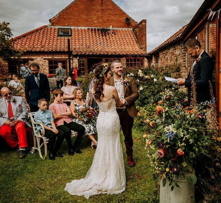 Outdoor Garden Wedding Ceremony with Milk Churn Filled with Bright Wedding Flowers