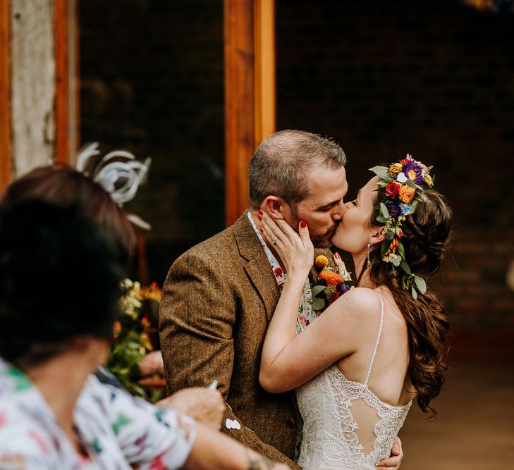 Bride in Lace Wedding Dress and Flower Crown Kissing at the Wedding Ceremony