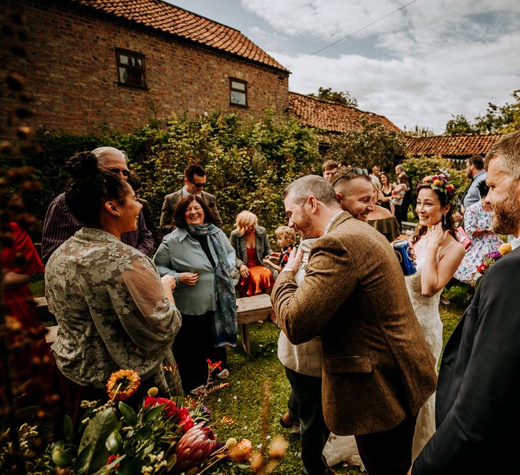 Groom in Wool Suit Being Congratulated by Wedding Guests