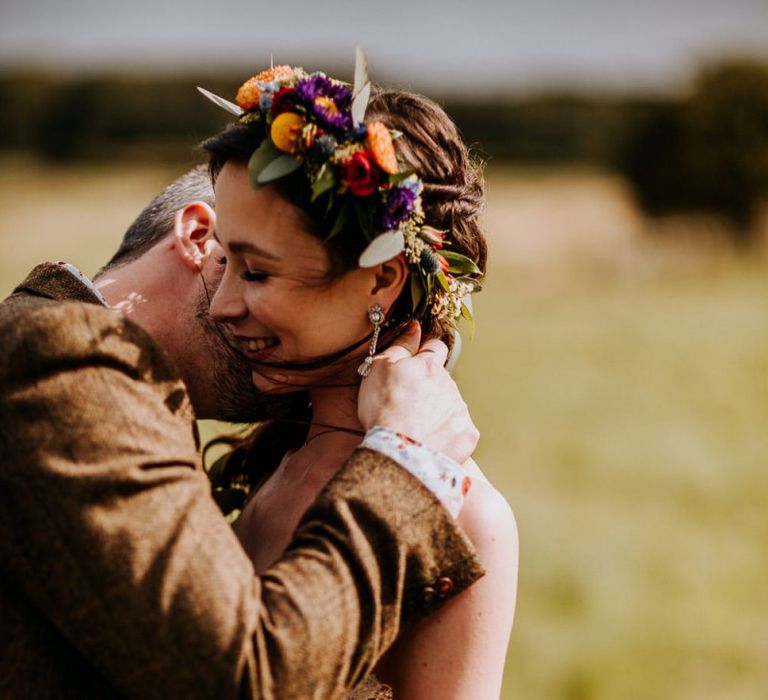 Groom in Brown Wool Suit Kissing His Bride in a Colourful Flower Crown