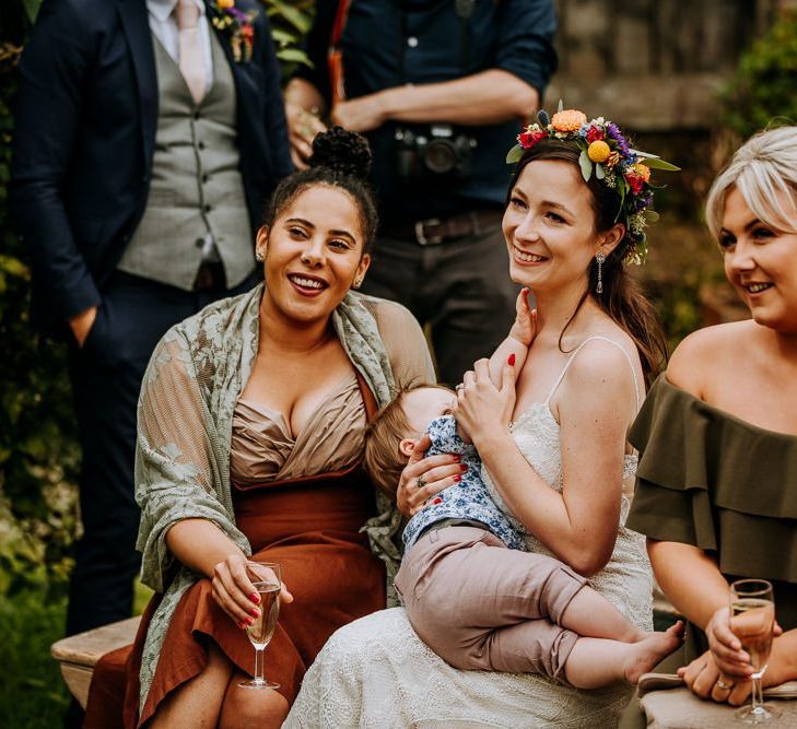 Bride Wearing a Colourful Flower Crown Sitting with Her Wedding Guests