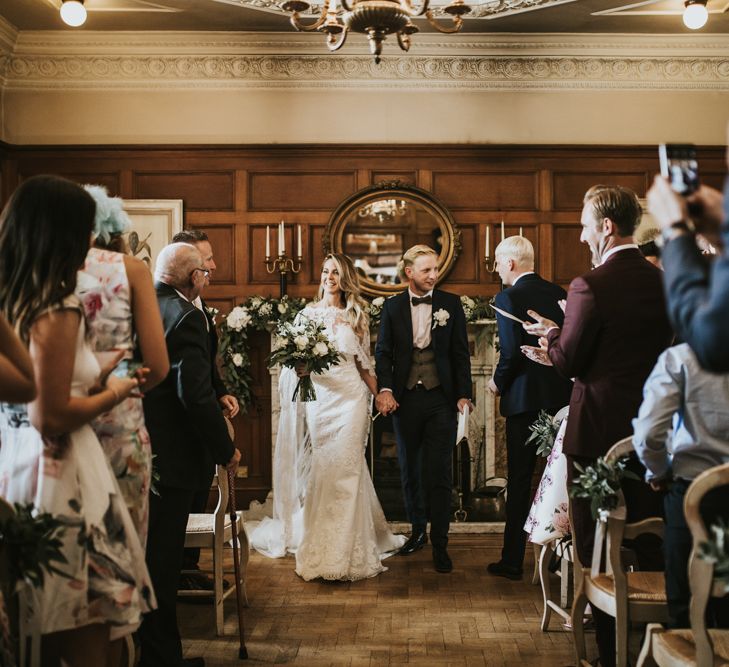 Wedding Ceremony | Bride in Pronovias Oringo Lace Bridal Gown &amp; Cape | Groom in Blue Marks and Spencer Suit | Green, White &amp; Gold Wedding at Buckland Tout Saints, Devon |  Darina Stoda Photography