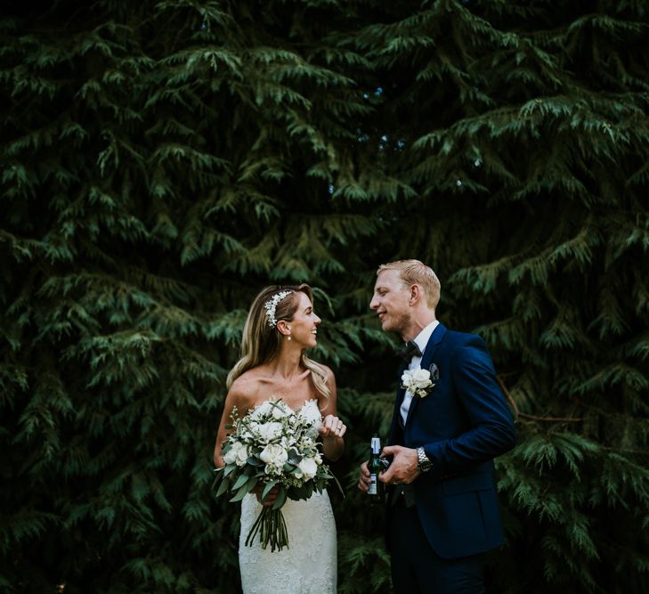 Bride in Pronovias Oringo Lace Bridal Gown &amp; Cape | Groom in Blue Marks and Spencer Suit | Green, White &amp; Gold Wedding at Buckland Tout Saints, Devon |  Darina Stoda Photography