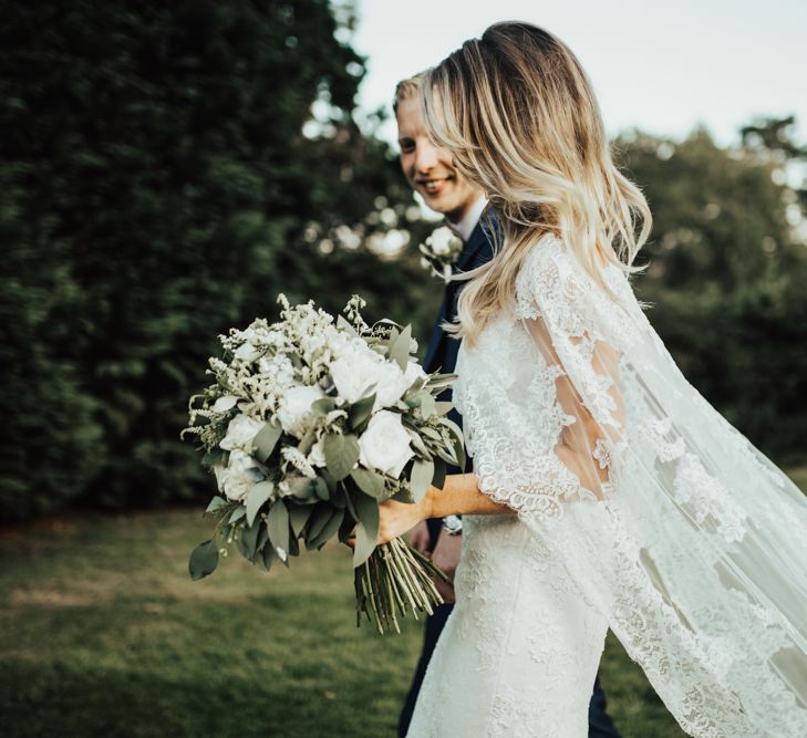 Bride in Pronovias Oringo Lace Bridal Gown &amp; Cape | Groom in Blue Marks and Spencer Suit | Green, White &amp; Gold Wedding at Buckland Tout Saints, Devon |  Darina Stoda Photography