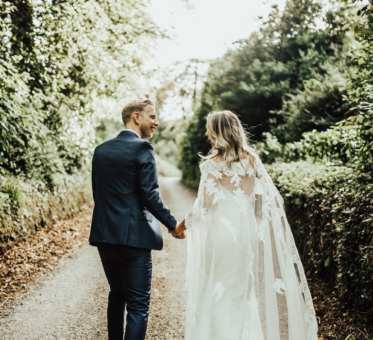 Bride in Pronovias Oringo Lace Bridal Gown &amp; Cape | Groom in Blue Marks and Spencer Suit | Green, White &amp; Gold Wedding at Buckland Tout Saints, Devon |  Darina Stoda Photography