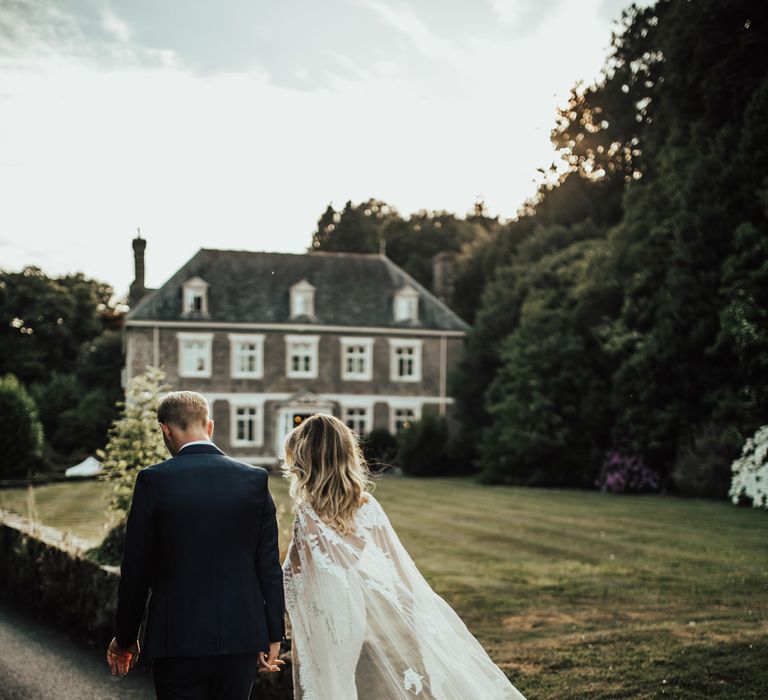 Bride in Pronovias Oringo Lace Bridal Gown &amp; Cape | Groom in Blue Marks and Spencer Suit | Green, White &amp; Gold Wedding at Buckland Tout Saints, Devon |  Darina Stoda Photography