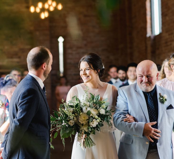 Bride greets groom at altar holding white wedding flowers bouquet