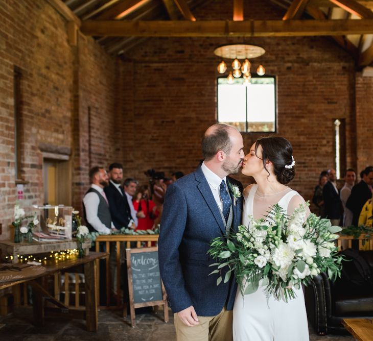 Bride and groom kiss after ceremony with white wedding flowers