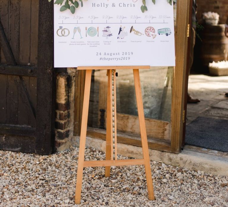 Wedding order of the day sign with icons decorated in white wedding flowers