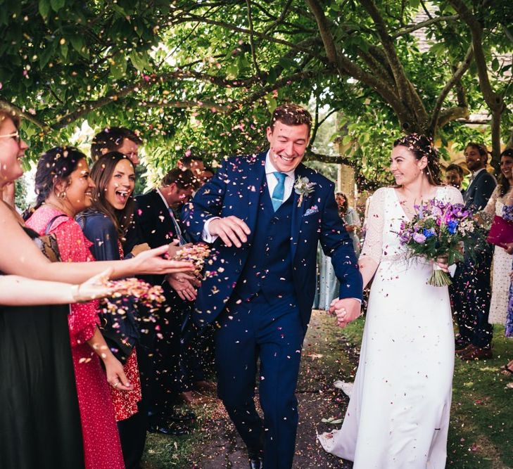 Bride and groom confetti exit with bright bouquet