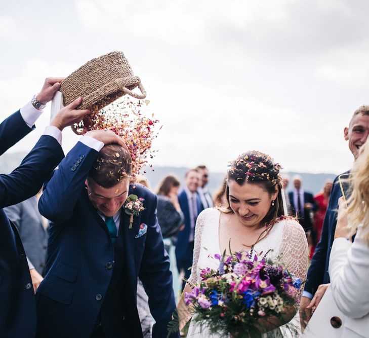 Bride and groom confetti exit with bright bouquet