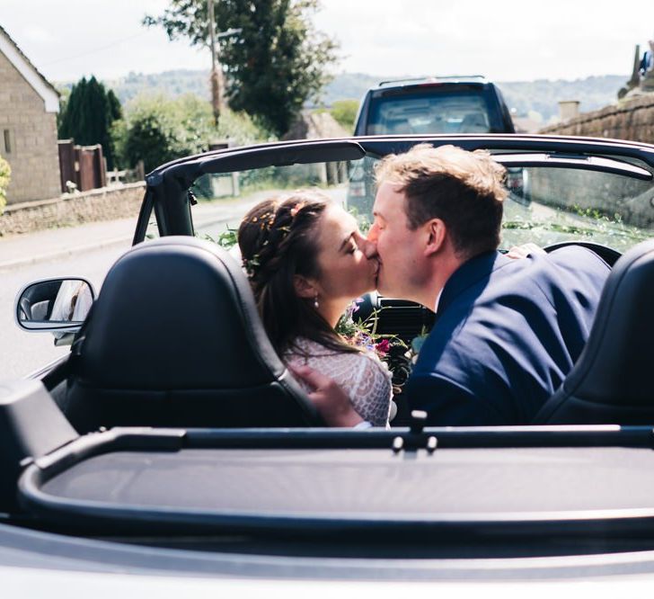 Bride and groom kiss in wedding car