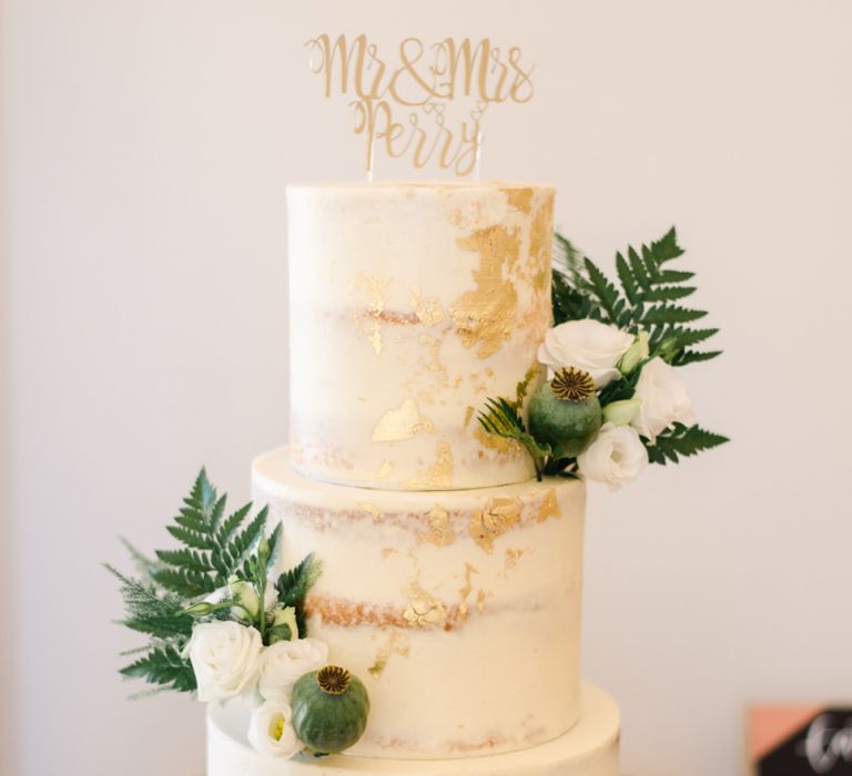 Semi-naked wedding cake with white wedding flowers and gold foil