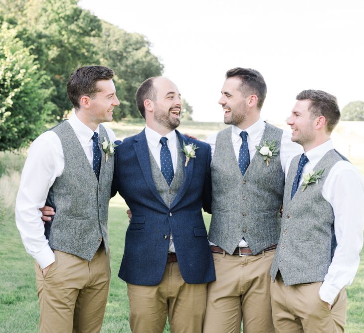 Groom in navy wedding jacket with groomsmen in matching grey waistcoats