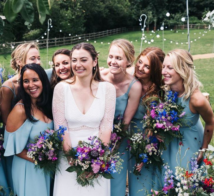 Blue bridesmaid dresses with wildflower bouquets to match the floral moon gate arch