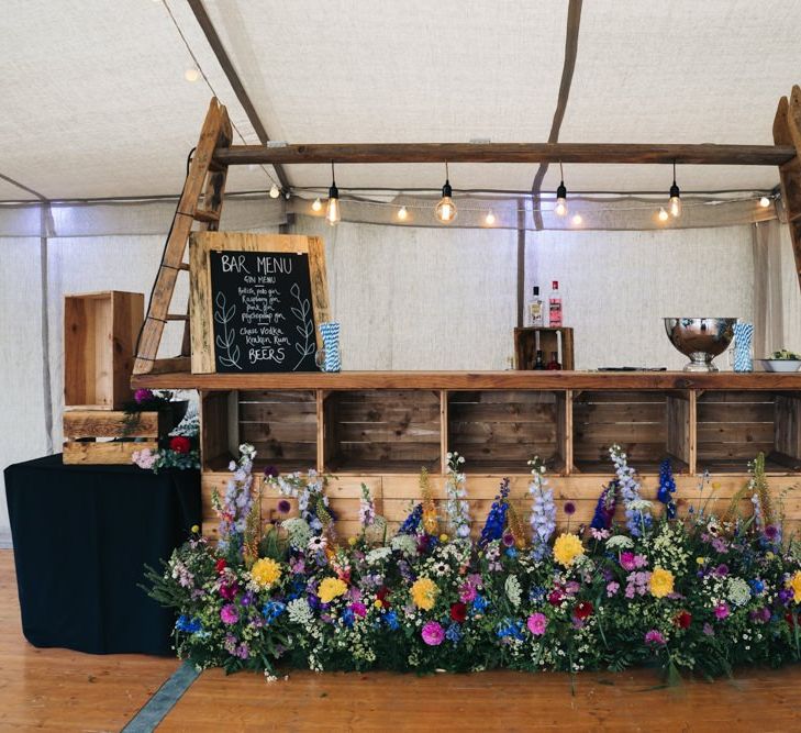 Wooden bar at wedding with bright flowers