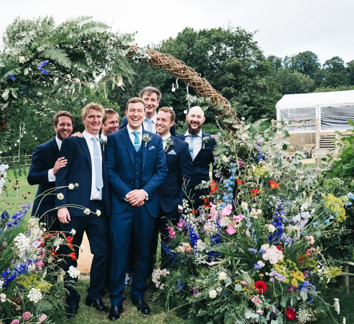 Groom and groomsmen in floral moon gate arch