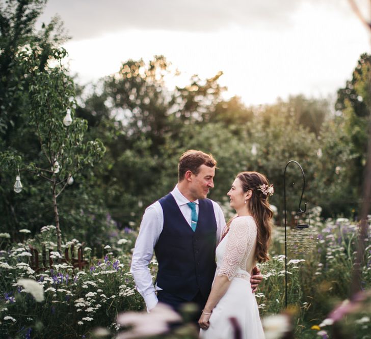 Bride and groom in wildflower orchard with wildflower moon gate arch