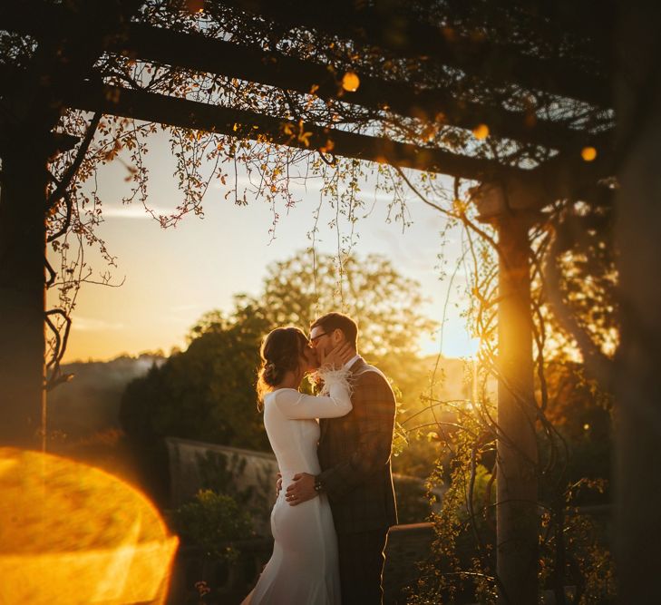 Sunset Wedding Portrait of Bride in Fitted Pronovias Wedding Dress and Groom in Checked Suit