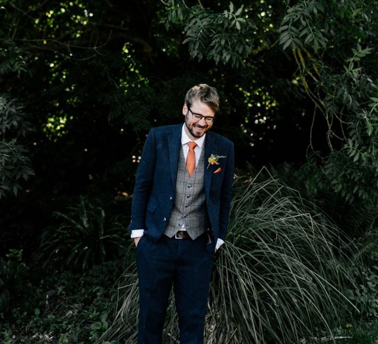 Groom in navy wool suit check waistcoat and orange tie