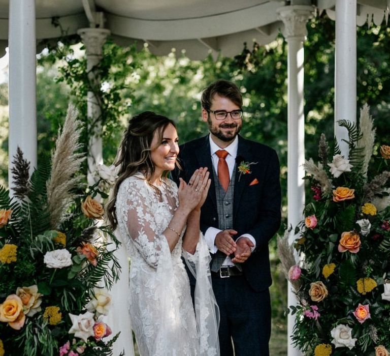 Boho bride and groom clapping at Preston Court wedding  ceremony