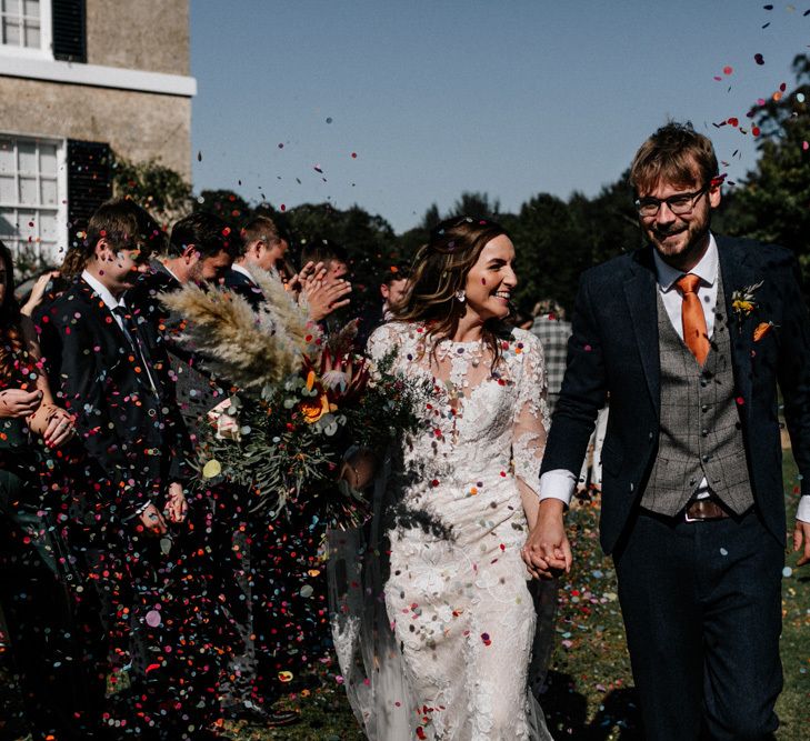 Bride in long sleeve Pronovias wedding dress and groom in check waistcoat and orange tie