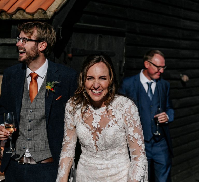 Bride in lace wedding dress with long sleeves laughing