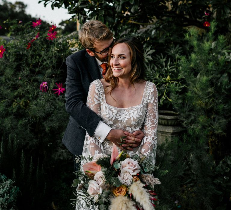 Groom embracing his bride in lace wedding dress