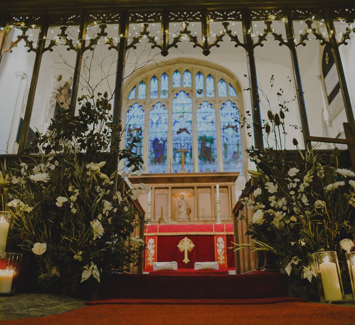 church altar decorated with fairy lights, foliage and candles