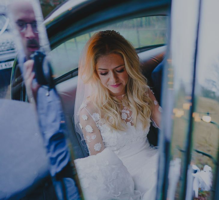 Bride in lace wedding dress getting out of the church wedding car