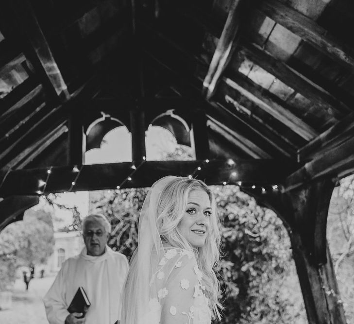 Bride in Rime Arodaky wedding dress in church courtyard