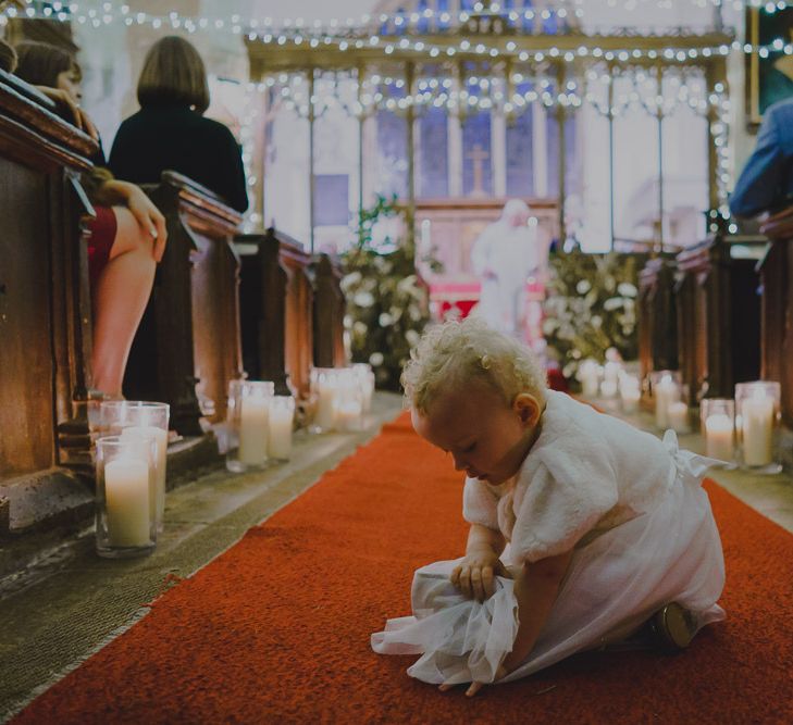 Baby flower girl playing in the church aisle during the ceremony