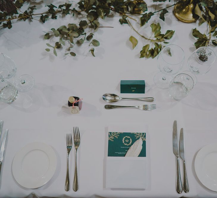 Place setting with green and white stationery and foliage table runner