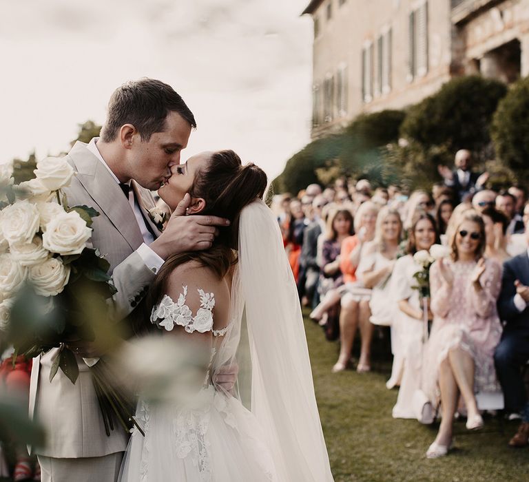 Bride and groom kiss at outdoor ceremony