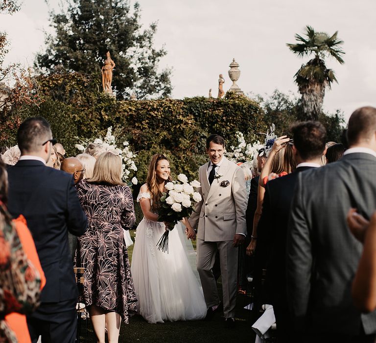 Bride in Galia Lahav dress and groom walk up the aisle