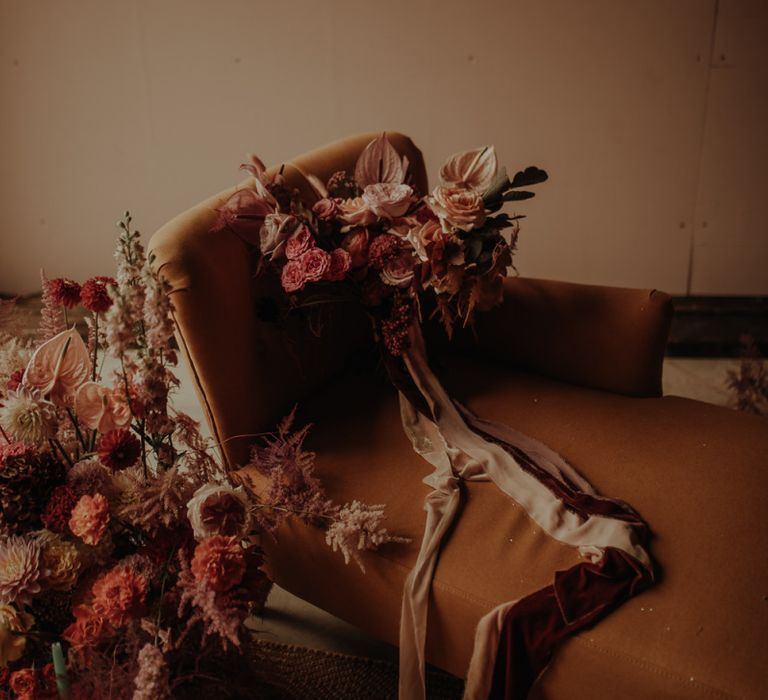 Pink wedding bouquet tied with ribbon resting on a chaise lounge